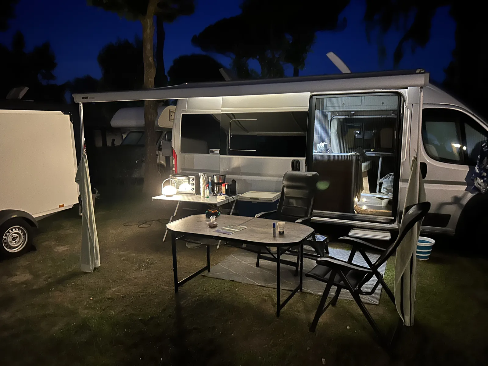 Camper met uitgeklapte luifel en tafel op de camping in Dormelletto bij avond