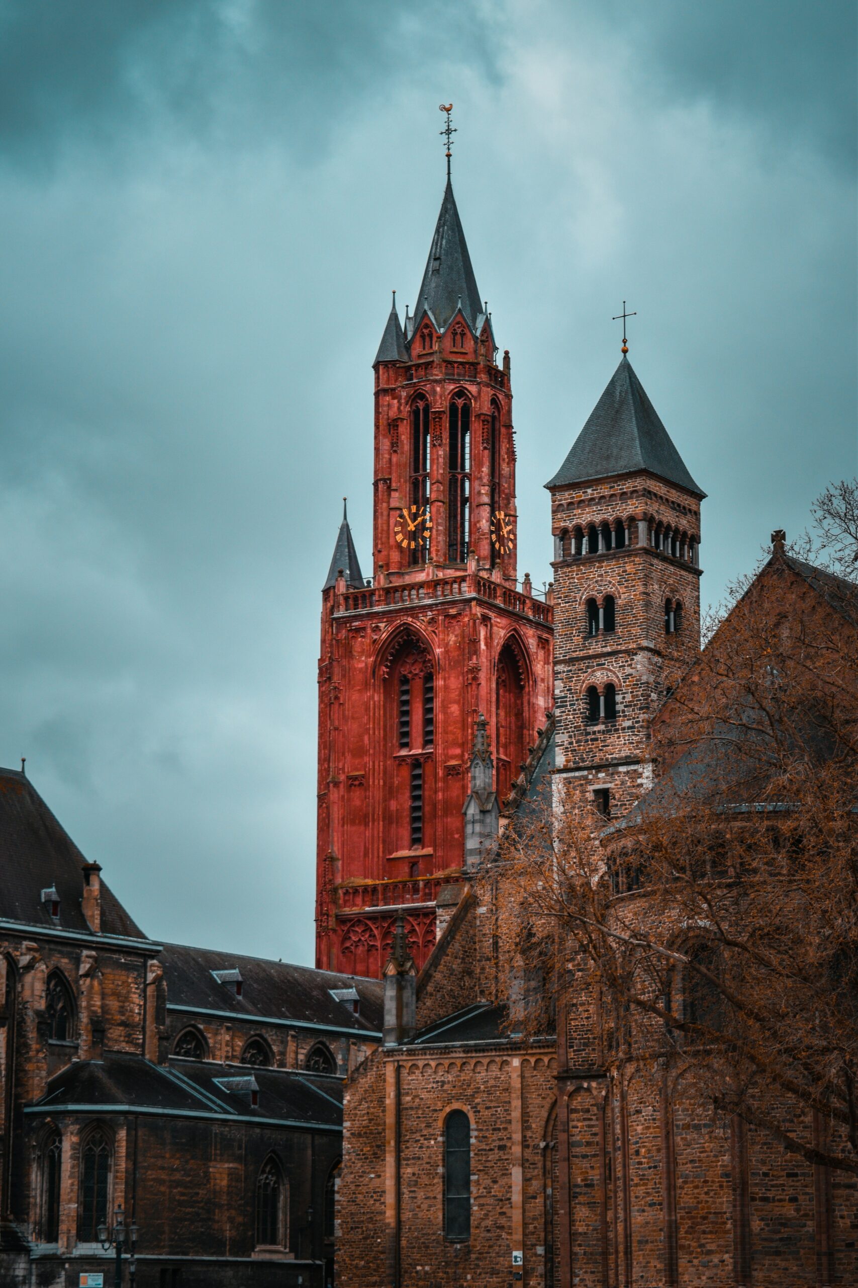 De rode toren van de Sint-Janskerk naast de Sint-Servaasbasiliek in Maastricht, onder een donkere lucht