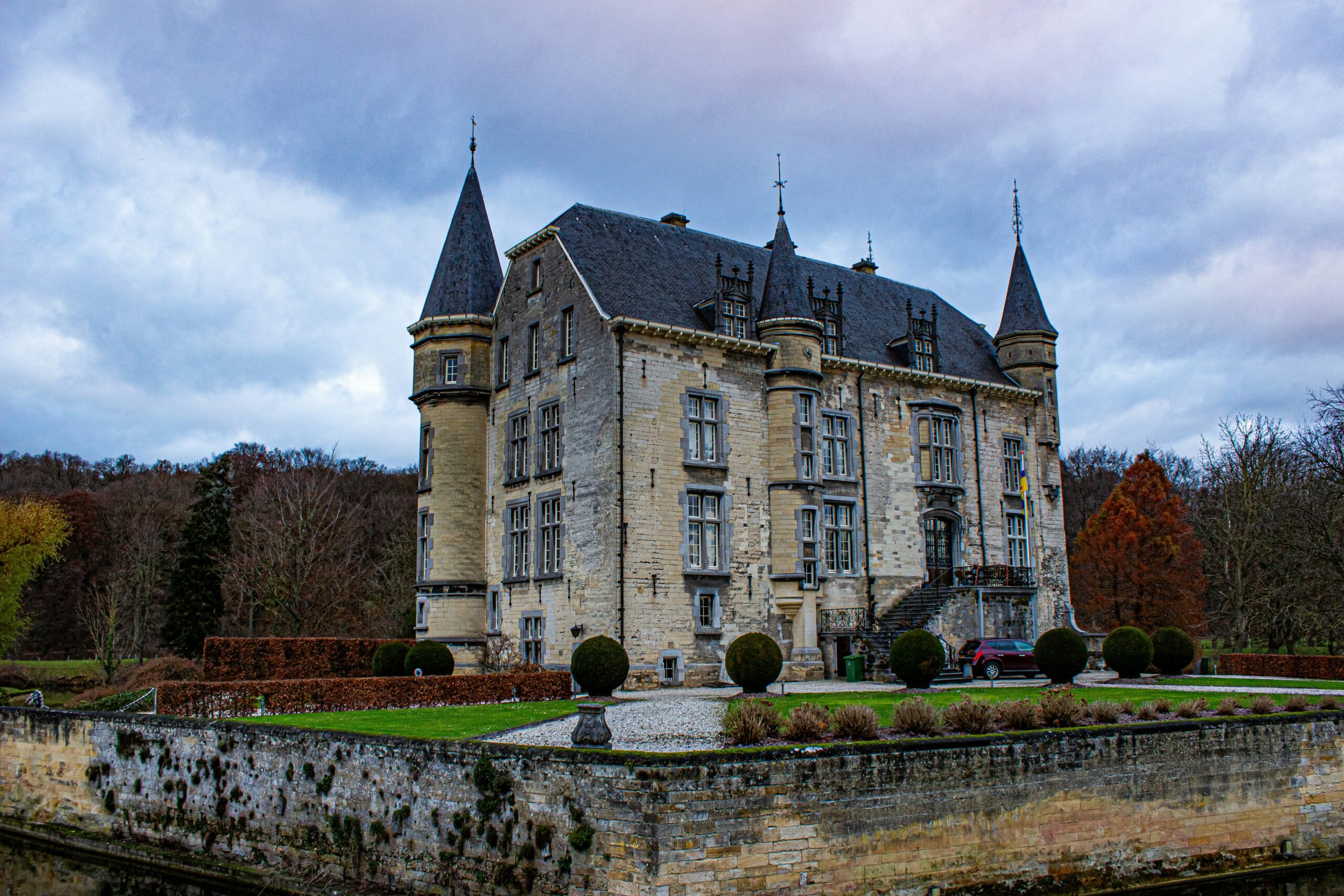 Kasteel Schaloen bij Valkenburg met torentjes en leien daken, achter een gracht en tuinmuur in herfstkleuren